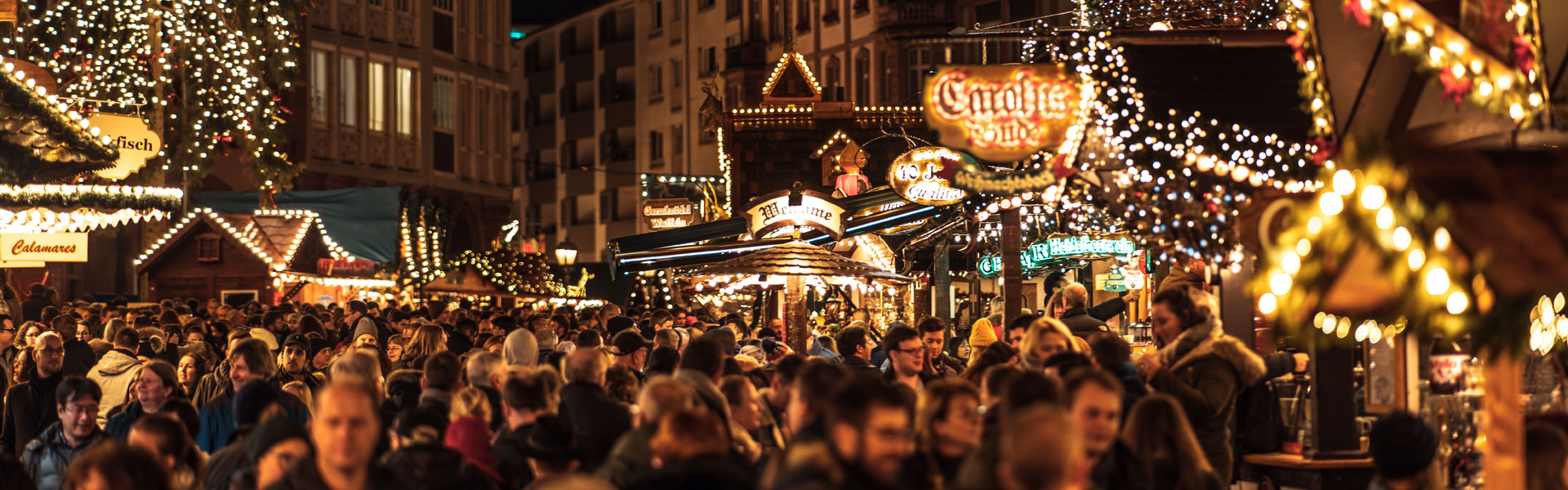 NIKOS auf einem Weihnachtsmarkt: beleuchtete Stände und Besucherströme